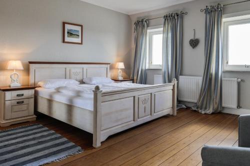una camera da letto con un grande letto bianco e due finestre di Lenas Hüs a List