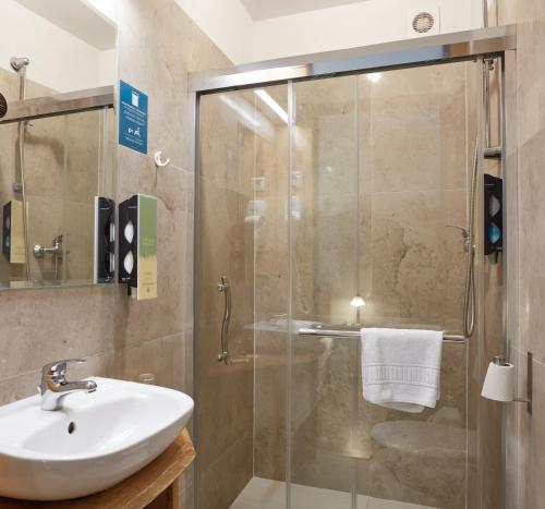 a bathroom with a sink and a glass shower at Batory Annex in Kraków