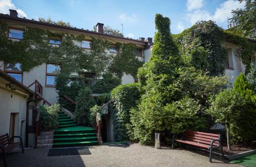 a building covered in ivy with a bench and stairs at Batory Annex in Krakow