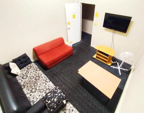 a living room with a couch and a tv at Surf 'N' Snow Backpackers Across Sky Tower in Auckland