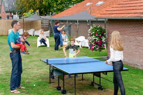 a group of people standing around a ping pong table at de Berkelstee in Eibergen