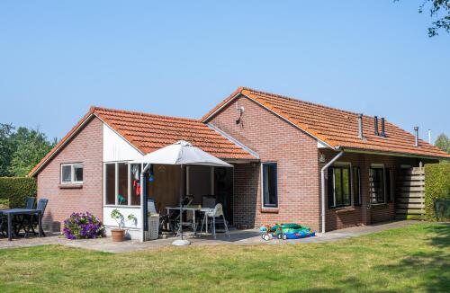 a small brick house with an umbrella and a table at de Berkelstee in Eibergen