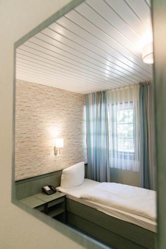 a mirror reflecting a bedroom with a bed and a window at Gästehaus Chorin in Chorin