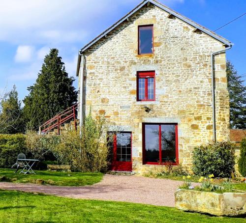 an old stone house with red doors and windows at le gite du jardinier in Saint-Martin-lʼAiguillon
