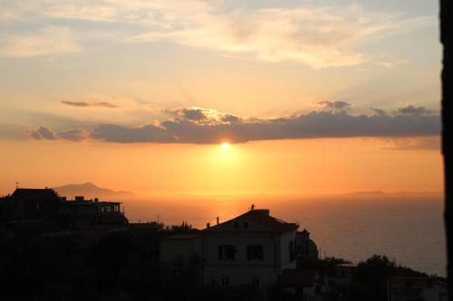 a sunset over the ocean with a house in the foreground at Hotel Il Nido Sorrento in Sorrento