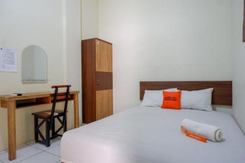 1 dormitorio con cama con almohada naranja y escritorio en KoolKost at Jl Unta Pandeyan Lamper Semarang - Minimum Stay 30 night, en Semarang