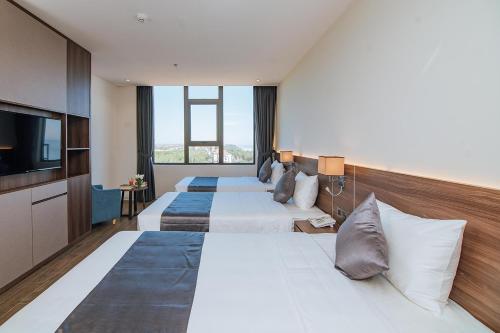 a hotel room with two beds and a flat screen tv at Phương Bắc Luxury Hotel in Dong Hoi