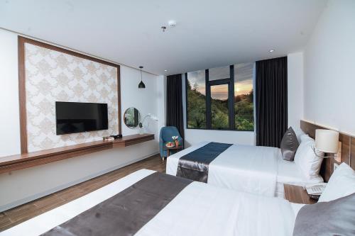 a hotel room with two beds and a flat screen tv at Phương Bắc Luxury Hotel in Dong Hoi
