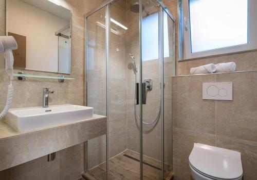Un baño con ducha, lavabo e inodoro. en Villa LiptovMara, en Ižipovce