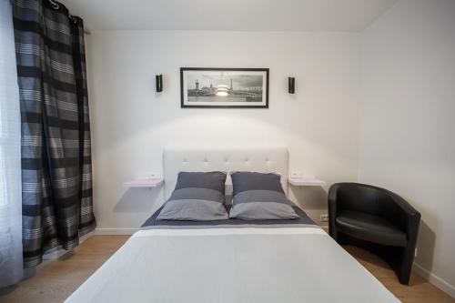 a white bed in a room with a black chair at NEAR EIFFEL TOWER - BEAUTiFUL FLAT in Paris