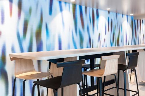 a table with four chairs and a wall with a colorful curtain at Oceania Paris Porte De Versailles in Paris