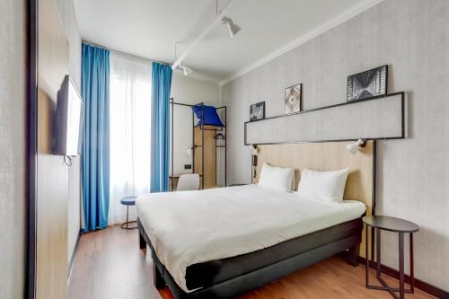 una habitación de hotel con una cama grande y cortinas azules en ibis Daumesnil Porte Doree en París