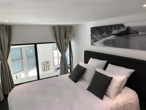 a bedroom with a white bed with pillows and a window at Loft des Sacres - Vue unique sur la Cathédrale in Reims