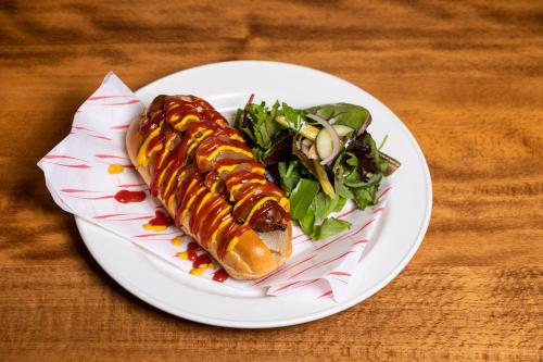 a white plate with a hot dog and a salad at Green Hotel in Kinross