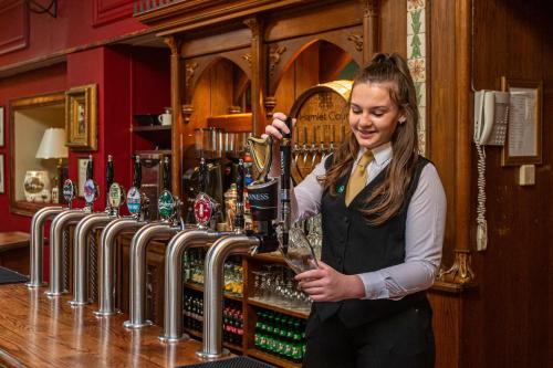 a woman holding a glass of wine in a bar at Hamlet Court Hotel in Enfield