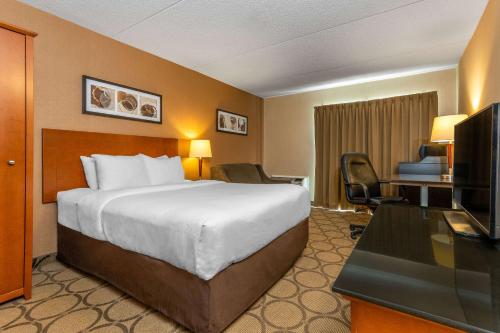 a hotel room with a bed and a desk and a television at Comfort Inn Timmins in Timmins