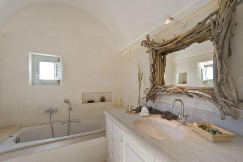 a bathroom with a sink and a tub and a mirror at w Villa Black Rock Santorini in Akrotiri