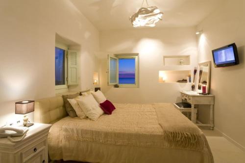 a bedroom with a bed and a desk and a television at w Villa Black Rock Santorini in Akrotiri