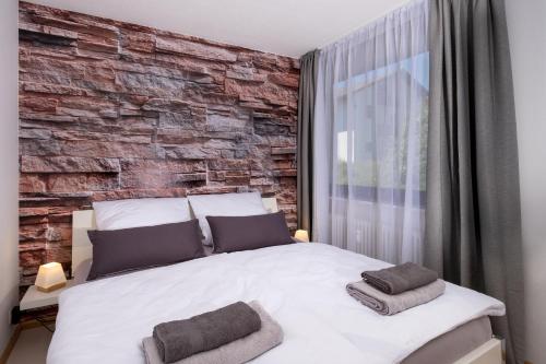 Un dormitorio con una pared de ladrillo y una cama en Black Forest Schwarzwaldblick Indoorpool Natur Ruhe Komfort, en Höchenschwand