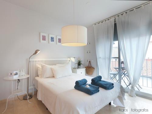 ein Schlafzimmer mit einem weißen Bett mit blauen Kissen darauf in der Unterkunft Encantador apartamento junto al Mediterraneo by Hometels in Puerto de Sagunto