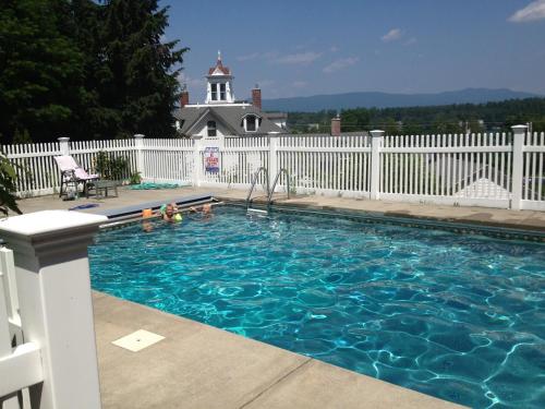 a swimming pool in front of a white fence at Center Harbor Sutton House B & B in Center Harbor