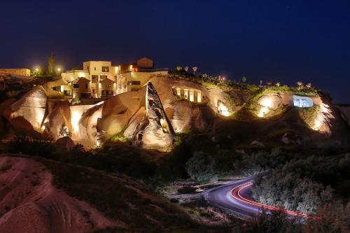 uma casa numa montanha à noite com luzes em Ariana Sustainable Luxury Lodge - Special Category - Cappadocia em Üçhisar