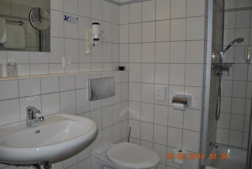 a white bathroom with a sink and a toilet at Heidehotel Lubast in Lubast