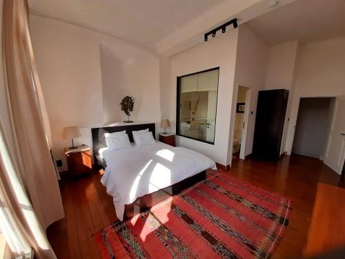 a bedroom with a white bed and a red rug at B&B at Haras Petit-Hallet in Hannut