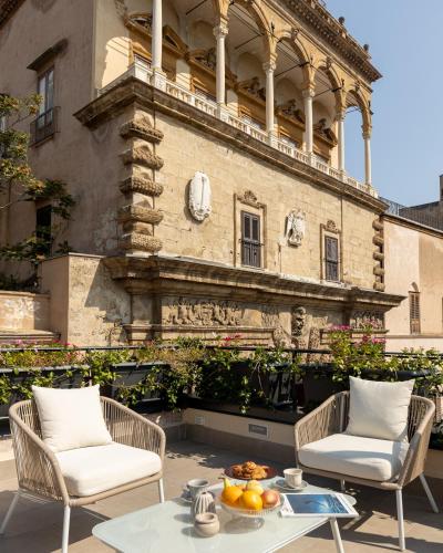 a patio with two chairs and a table in front of a building at I Mori di Porta Nuova Suite & Terrace in Palermo