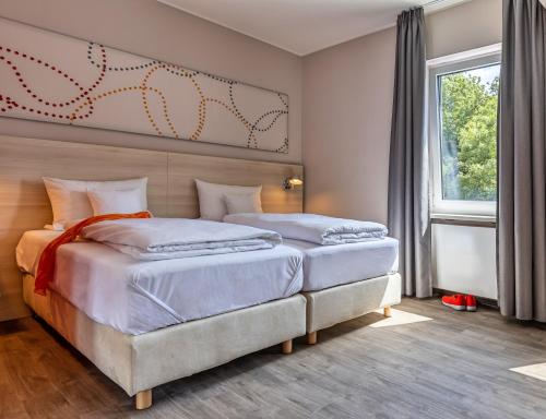 a bedroom with two beds and a large window at Serways Hotel Rhynern-Süd in Hamm