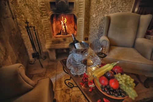 a table with a plate of fruit and a glass of wine at Traveller's Cave Hotel in Goreme