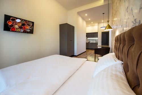 a bedroom with a white bed and a kitchen at Central Dayflat Apartments in Kyiv