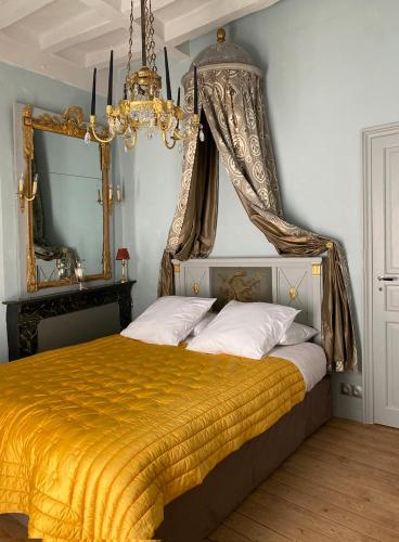 sypialnia z łóżkiem z żółtym kocem i żyrandolem w obiekcie Manoir de Ghaisne w mieście Freigné
