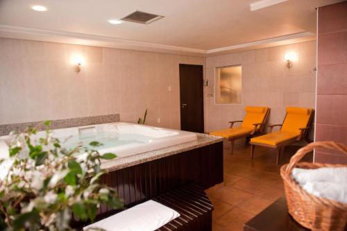 Maitá Palace Hotel في باسو فوندو: حمام كبير مع حوض استحمام وكراسي