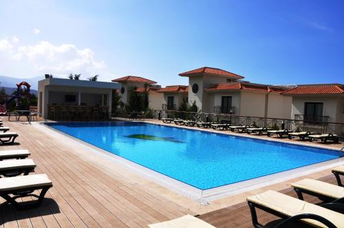 a large swimming pool with lounge chairs on a deck at Korineum Golf & Beach Resort in Kérynia