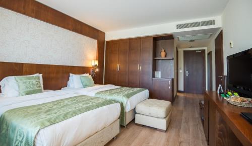 a hotel room with two beds and a flat screen tv at Korineum Golf & Beach Resort in Kérynia