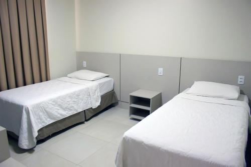a room with two beds and a night stand in a room at Sudoeste Hotel in Goiânia