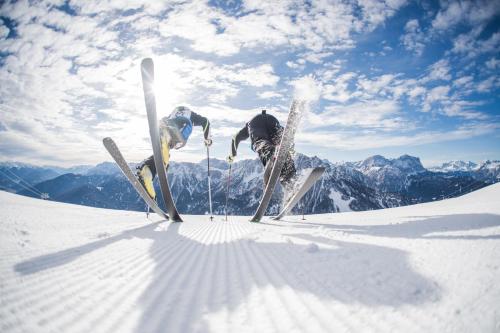 a person jumping in the air on skis in the snow at Hotel Fameli in Valdaora