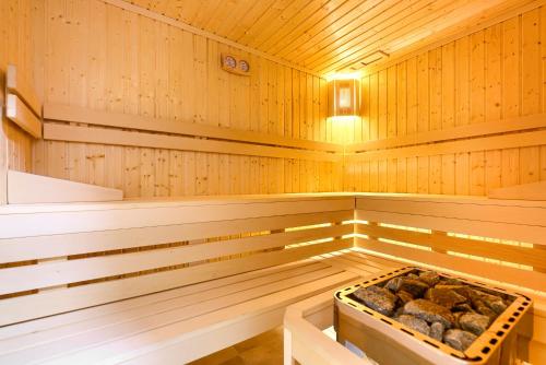 een houten sauna met een dienblad met rotsen erin bij Olimpijska 2 - City Apartments in Mielno