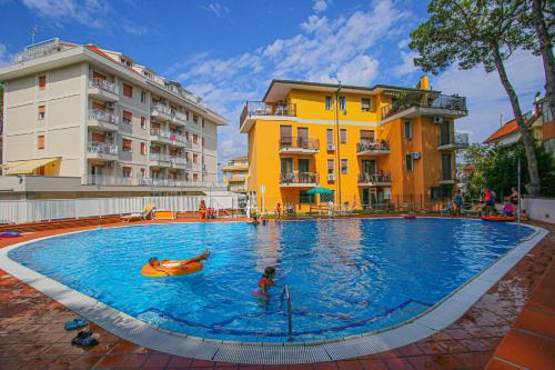 una grande piscina con due persone in acqua di Residences La Rustica & Elite a Eraclea Mare
