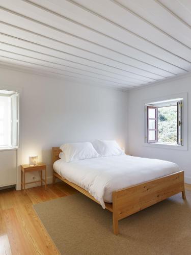 a white bedroom with a large bed with a window at Quinta da Caída in Arcas