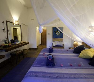a bedroom with two beds with a canopy at Sunbird Chintheche in Nkhata Bay