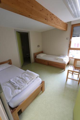 1 dormitorio con 2 camas en una habitación con ventana en Auberge de Jeunesse HI Pontarlier, en Pontarlier