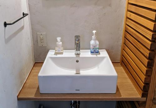 a white bathroom sink with two soap bottles on it at 神倉書斎 [Kamikura-Hideaway] in Shingu