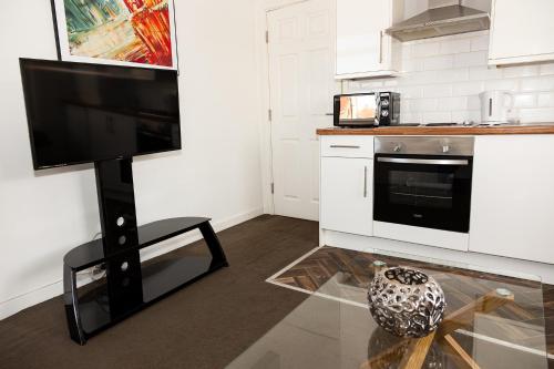 a kitchen with a flat screen tv on a stand at Alexander Apartments Roker in Sunderland