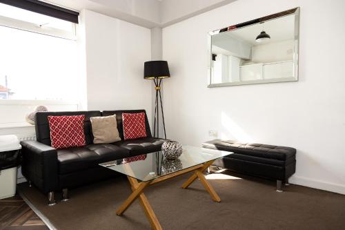 a living room with a black couch and a glass table at Alexander Apartments Roker in Sunderland