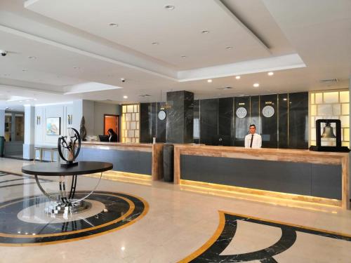 a lobby with a bar with a man in the background at Royal Jewel Al Raml Hotel in Alexandria