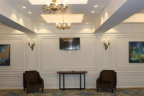 a room with two chairs and a table and a tv at Royal Jewel Al Raml Hotel in Alexandria