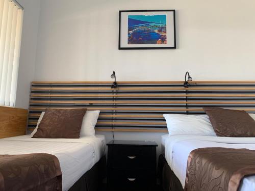 a hotel room with two beds and a picture on the wall at Baths Motel Moree in Moree