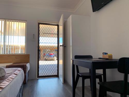 a room with a bed and a desk and a door at Baths Motel Moree in Moree